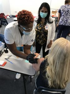 Keiser University Nursing Student Mirline Torchin prepares to administer a vaccine under the guidance of Dr. Maureen Harry 